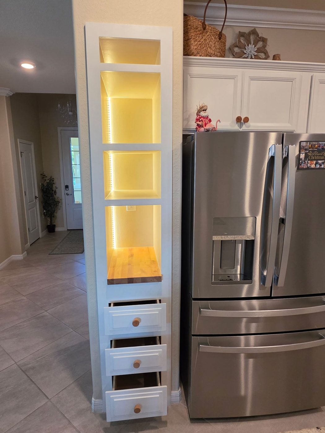 Custom built-in storage tower with LED-lit niches and butcher block shelf