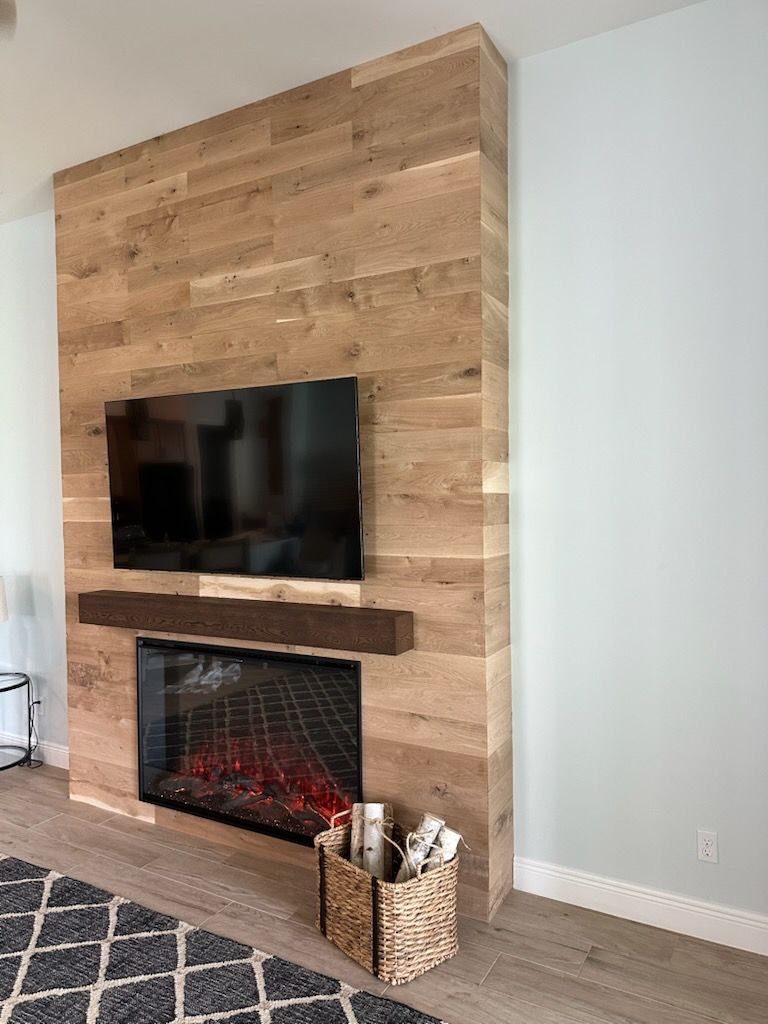 Wood plank accent wall with mounted TV and fireplace