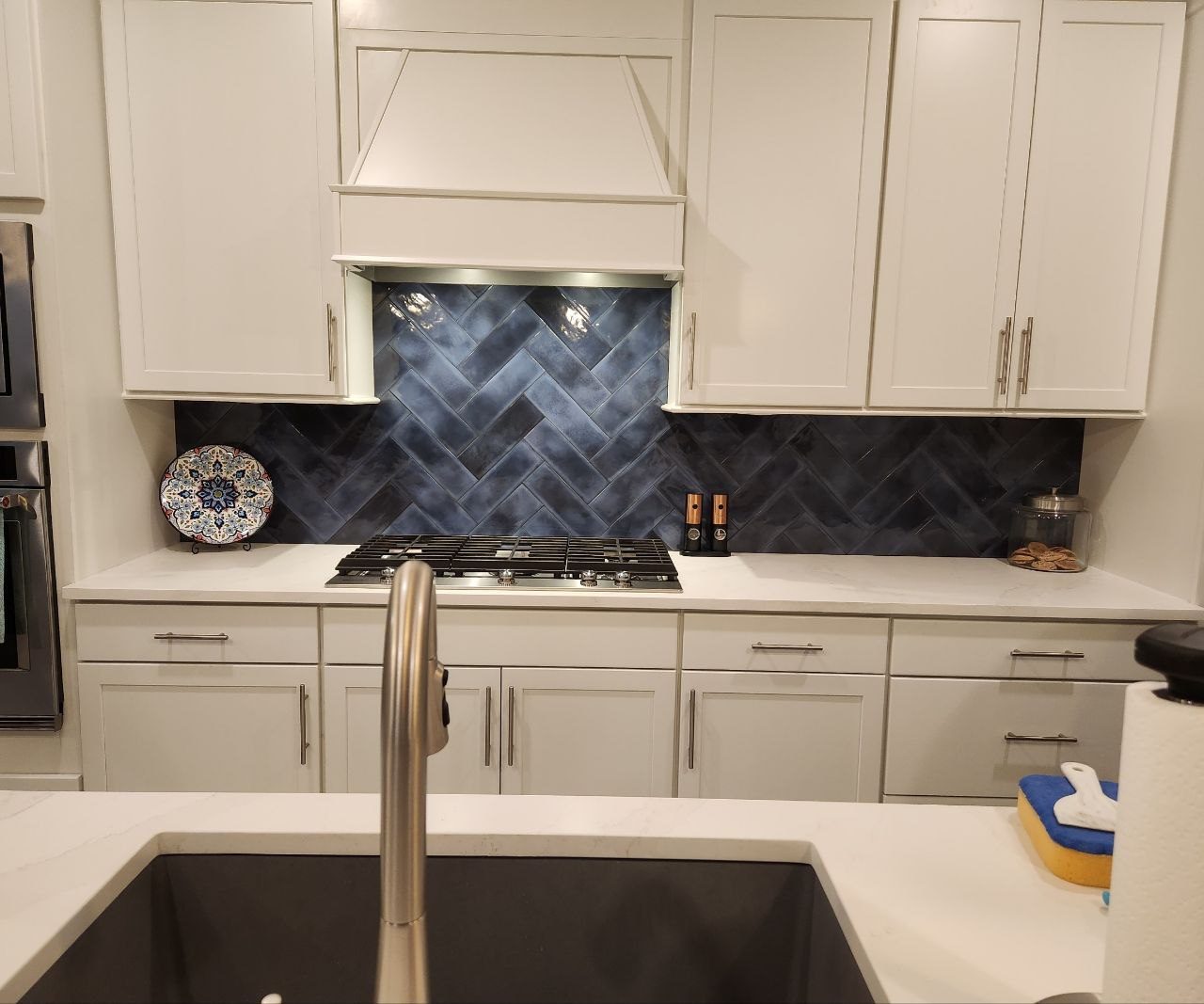 Herringbone tile backsplash and custom range hood