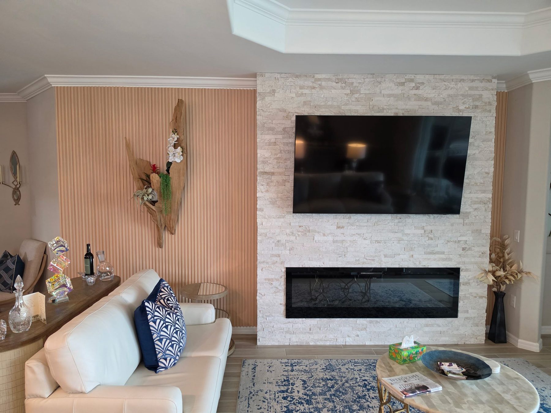 Stacked stone fireplace wall with mounted TV and fluted wood accent wall